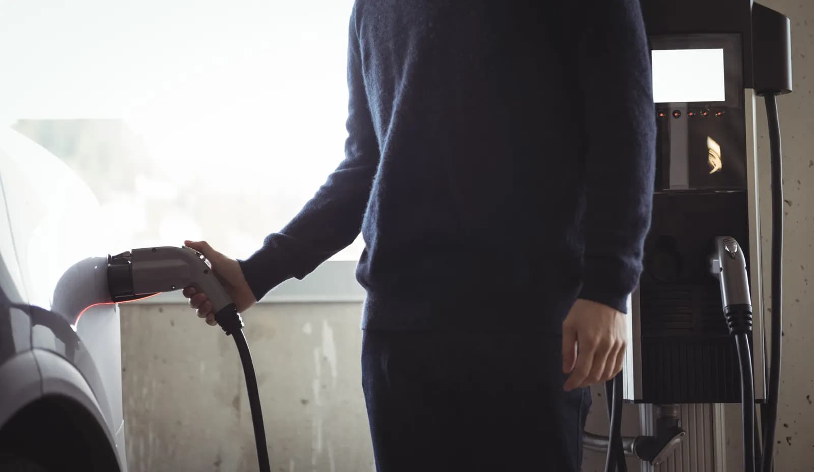 Person som lader en elbil på en ladestasjon